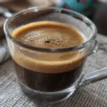 Jennifer Aniston collagen coffee with MCT oil and cinnamon in a glass mug on wooden table – healthy intermittent fasting drink